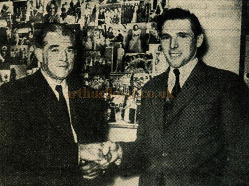 With photographs of his famous Windmill girls decorating the office wall in the background, Mr. Vivian Van Damm (left), brains behind the famous theatre, welcomes visitor Cyril Roger. Mr. Van Damm was associated with speedway racing in the early days of the sport. 