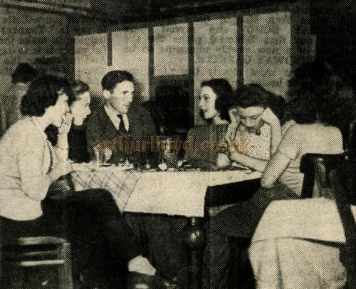Caption Reads: With such charming companions I wish the lunch session could last for ever!" sighed Cyril as he joined the Windmill ladies in their canteen above the theatre. The girls wanted to know what it was like to be a speedway hero.