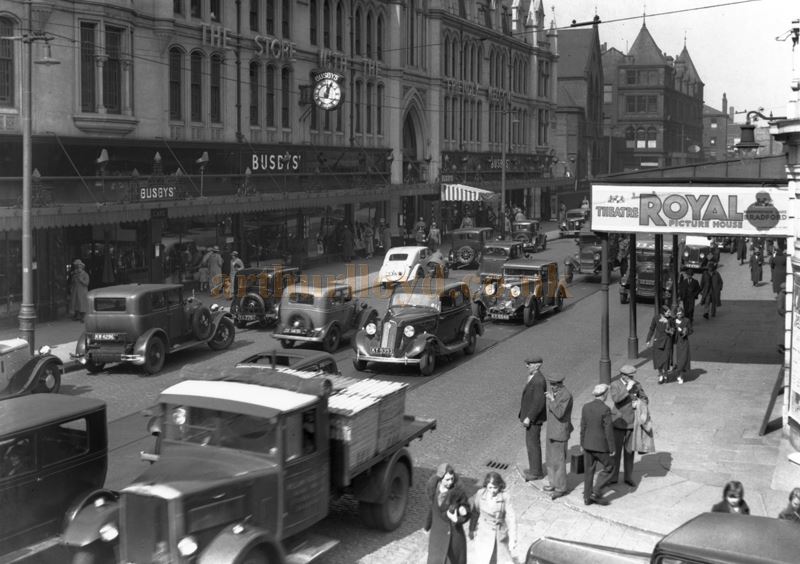 A photograph showing the department store 'Busbys' and the canopy of the Theatre Royal Picture House, Bradford by C. H. Wood - With kind permission © Bradford Museums & Galleries.